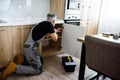 Full length shot of aged repairman in uniform working, fixing kitchen cabinet using screwdriver. Repair service concept