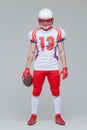 Full length shot of american football sportsman player wearing helmet holding rugby ball isolated on grey background Royalty Free Stock Photo