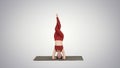 Beautiful young woman doing yoga exercise variation of supported headstand, garuda salamba sirsasana with crossed legs