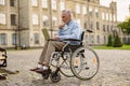 Full length shot of busy mature man, recovering patient in wheelchair working on a laptop outdoors in the park near