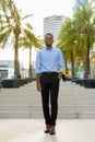 Full length shot of handsome black African businessman outdoors in city during summer smiling and walking Royalty Free Stock Photo