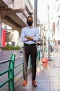 Full length shot of handsome black African businessman outdoors in city during summer wearing face mask Royalty Free Stock Photo
