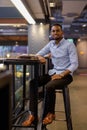 Full length shot of of handsome black African businessman sitting inside shopping mall Royalty Free Stock Photo