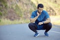 Trying to bring my heart rate back down. Full length shot of a handsome young man crouching and timing his pulse during