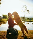 Whos a big boy. Full length shot of a handsome young man and his dog spending the day by a lake in the park. Royalty Free Stock Photo