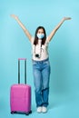 Full length shot of happy asian girl tourist, wearing face medical mask, standing near cute suitcase, going on vacation