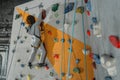 Full-length shot of little boy in a harness climbing a wall with grips