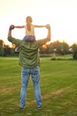 Full length shot of little girl sitting on her father`s shoulders while they enjoying sunset together, daughter and Royalty Free Stock Photo