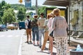 Full length shot of people wearing masks waiting, standing in line, keeping social distance at bus stop. Coronavirus