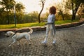 Full-length shot of pretty healthy young lady walking in the morning in park with dog