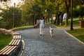 Full-length shot of pretty healthy young lady walking in the morning in park with dog