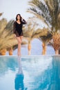 Full length shot of a slim young woman in swimwear at the poolside. Woman standing on the edge of the pool and looking away. Royalty Free Stock Photo