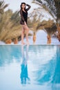 Full length shot of a slim young woman in swimwear at the poolside. Woman standing on the edge of the pool and looking away. Royalty Free Stock Photo