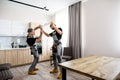 Full length shot of two electricians, workers in uniform installing electric lamp, light inside apartment in the kitchen