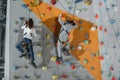 Full-length shot of two little kids in harnesses climbing a wall with grips Royalty Free Stock Photo