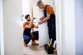 Full length shot of two locksmith, repairmen, workers in uniform installing, working with house door lock using Royalty Free Stock Photo