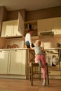 Full length shot of two naughty kids, brother and sister trying to find something sweet in the kitchen cupboard. Little