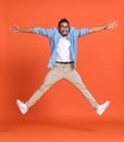 Full length shot of young emotional overjoyed african american man jumping over orange background