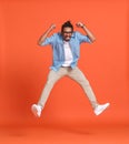 Full length shot of young emotional overjoyed african american man jumping over orange background Royalty Free Stock Photo