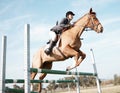 Over we go. Full length shot of a young female rider jumping over a hurdle on her horse.