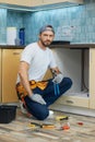 Full length shot of young handyman, professional plumber wearing tool belt looking at camera while fixing a sink in the Royalty Free Stock Photo