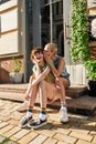 Full length shot of young lesbian couple, two girls gossiping, smiling, sitting on the steps while having a walk around Royalty Free Stock Photo