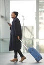 Full length happy african american travel man walking at airport with mobile phone and suitcase Royalty Free Stock Photo