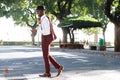 Full length smiling young black man in suit walking with mobile phone on street Royalty Free Stock Photo