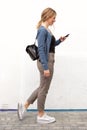 Full length young woman walking with mobile phone against white wall Royalty Free Stock Photo