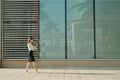 Full length side portrait of a young woman walking and sending text message on cell phone Royalty Free Stock Photo