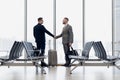 Full length side view of businessmen shaking hands in airport terminal Royalty Free Stock Photo