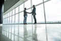 Full length side view of businessmen shaking hands in office building windows background Royalty Free Stock Photo