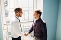 Full length side view of businessmen shaking hands in office building Royalty Free Stock Photo