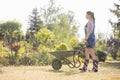 Full-length side view of female gardener pushing wheelbarrow at plant nursery