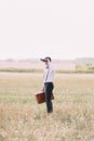 The full-length side view of the groom carrying the vintage suit and looking through the binoculars at the sky. Field Royalty Free Stock Photo