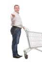 Full length side view of handsome young man standing with shopping trolley and looking at camera Royalty Free Stock Photo