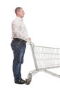 Full length side view of handsome young man standing with shopping trolley and looking at camera Royalty Free Stock Photo