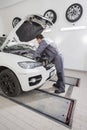 Full length side view of male automobile mechanic repairing car engine in repair shop