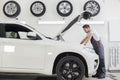 Full length side view of male mechanic examining car engine in repair shop Royalty Free Stock Photo