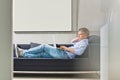 Full-length side view of Middle-aged man using laptop while lying on sofa Royalty Free Stock Photo
