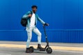 Full length side view of modern african american man with briefcase riding electric scooter on his way to work Royalty Free Stock Photo