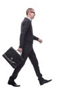 Full length side view picture of a young business man walking with a suitcase in his hand and a smile on his face Royalty Free Stock Photo