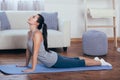 Full length side view portrait of beautiful young woman working out at home, doing yoga or pilates exercise on wooden