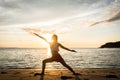 Silhouette of a fit woman practicing the warrior yoga pose at sunset Royalty Free Stock Photo