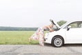 Full-length side view of woman examining broken down car on country road Royalty Free Stock Photo