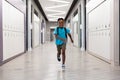 Full length of smiling african american elementary schoolboy running in corridor at school