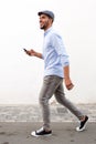 Full length smiling man walking with cellphone against white wall Royalty Free Stock Photo
