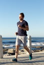 Full length sports man jogging outside by the sea Royalty Free Stock Photo