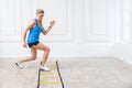 Full length of sporty beautiful young athletic blonde woman in black shorts and blue top are hard working and training on agility Royalty Free Stock Photo