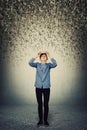 Full length of student boy looking up puzzled, holding books on head as multiple letters falling down as a rain of knowledge.